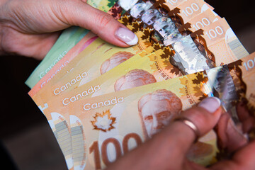 closeup on Canadian dollars in various denominations. A woman is counting Canadian money. Canadian...