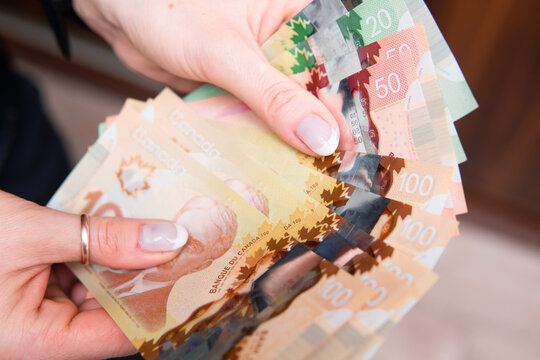 Closeup On Canadian Dollars In Various Denominations. A Woman Is Counting Canadian Money. Canadian Economics And Finance