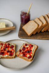 Bread with butter and cranberry jam is on the table and ready to eat. A delicious and sweet breakfast. Aesthetically pleasing serving of food. Recipe for toast with butter and jam.