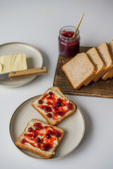 Bread with butter and cranberry jam is on the table and ready to eat. A delicious and sweet breakfast. Aesthetically pleasing serving of food. Recipe for toast with butter and jam.