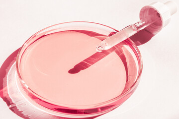 Petri dish. With pink liquid. With solution. Cosmetic pipette. On a white background.