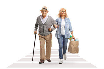 Woman crossing street and helping her senior father with grocery bags