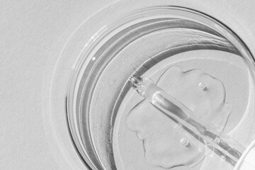 Petri dish. With transparent gel. The pipette lies. Cosmetic dispenser. On a white background.