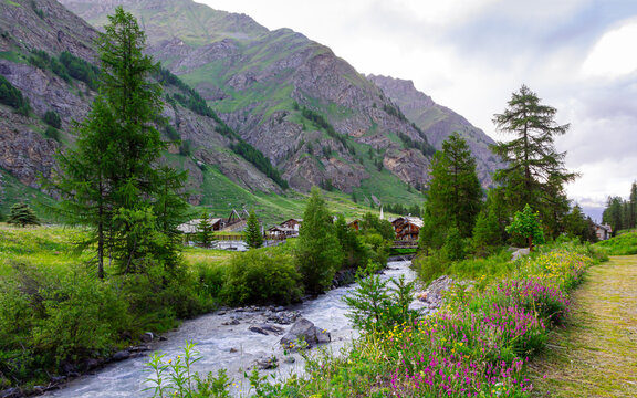 Il paesino di Rh&ecirc;mes Notre Dame visto dall'altra parte del fiume al crepuscolo in estate. Panorama in Val di Rhemes col paese il sentiero il torrente le montagne e le vette. Alpi Italia. Valle d'Aosta