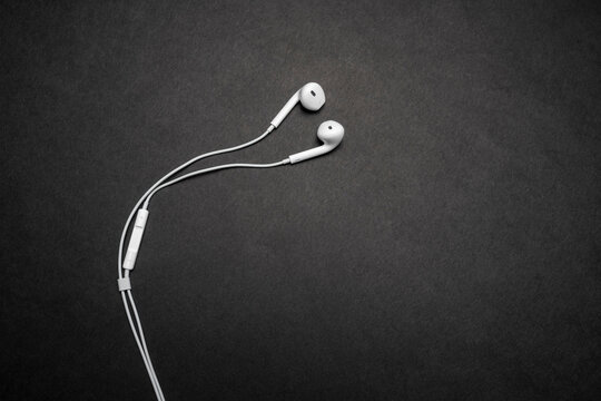 iPhone Apple Earpods, Airpods white earphones, headphones for listening to music and podcasts. Isolated black background. Budapest, Hungary - February 16, 2023