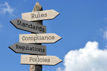 Rules, standards, compliance, regulations, policies - wooden signpost with five arrows, sky with clouds
