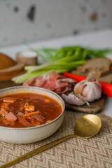 The traditional Ukrainian first course is red borsch. Hot borsch on the table with garlic, pepper, salt, onions and Ukrainian rye bread. Recipe for borsch with vegetables