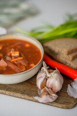 The traditional Ukrainian first course is red borsch. Hot borsch on the table with garlic, pepper, salt, onions and Ukrainian rye bread. Recipe for borsch with vegetables