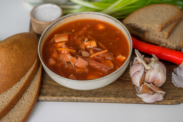 The traditional Ukrainian first course is red borsch. Hot borsch on the table with garlic, pepper, salt, onions and Ukrainian rye bread. Recipe for borsch with vegetables