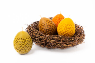 Traditional Easter decor. Burning soy candles in the form of multi-colored eggs in a nest and...