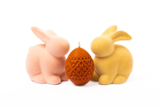 Traditional Easter decor. Burning soy candles in the shape of colorful eggs and an Easter bunny isolated on a white background. Happy easter.Colorful easter candles and flowers on background.