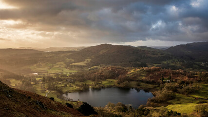 Stunning colorful Winter sunrise golden hour landscape view from Loughrigg Fell across the countryside in the Lake District