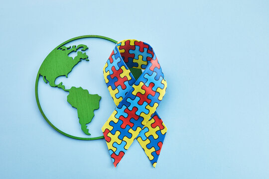 World Autism awareness and pride day or month with Puzzle pattern ribbon on blue background