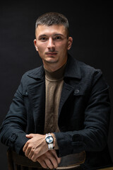 Young successful stylish man. Classical portrait of a businessman dressed in a jacket with a watch on his hand.