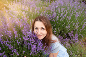 Attractive young female outdoors.Relaxed woman breathing fresh air sitting in a lavender field a sunny day. portrait of a smiling young beautiful girl