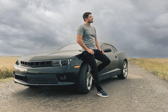 sexy man and black sports car. Handsome guy traveling by his car.  Sportive man. guys love toys