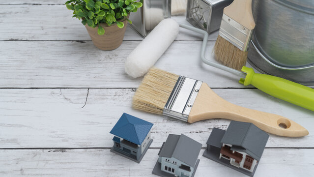 DIY・リフォーム・塗装業者　イメージ 　模型の家と塗装道具と白い木目背景