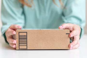 Woman holding in hands goods delivered in cardboard box