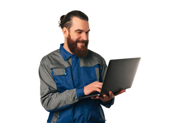 Smiling bearded man wearing engineer uniform is working on the laptop.