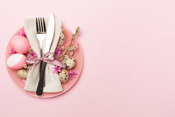 Easter table setting with spring flowers and cutlery on color background, top view
