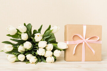 White tulip bouquet with gift box on table