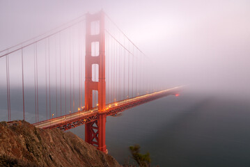 View of Golden gate bridge shrouded in thick fog at dusk in autumn