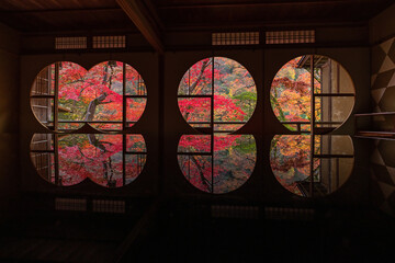 日本　京都府京都市の嵯峨嵐山にある祐斎亭の丸窓の部屋の机に反射して映る雨に濡れた紅葉
