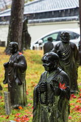 日本　京都府京都市の嵐山羅漢にある雨に濡れた羅漢像と紅葉