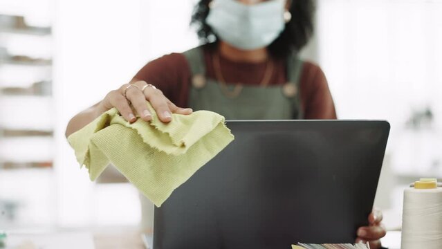 Covid, cloth and a business black woman cleaning her computer in the office at work for disinfection. Hand, hygiene or sanitizer with a female employee wiping a desktop monitor for health regulations