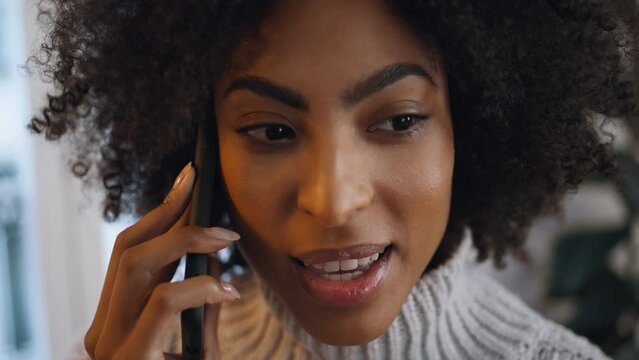 Positive woman calling smartphone at home close up. African lady sharing secrets