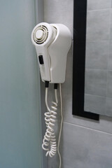 White hair dryer hanging on the wall in bathroom