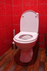 Toilet room with toilet bowl, toilet brush and red wall tiles