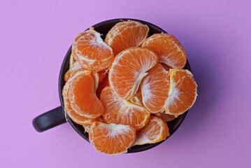 a meal of fresh red pieces of orange fruit in a brown cup stands on a pink table