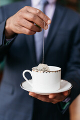 man putting a teabag into a china teacup 