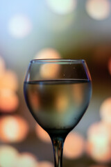 Vertical close up glass cup filled with wine and light bokeh in background 