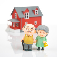 Obraz na płótnie Canvas miniature people. a couple of retired people near the house model on a white background. financial security and pension for the elderly. concept of financial independence
