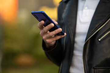 Closeup shot of an unrecognizable young man holding mobile phone in hand, blurred background