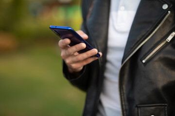 Unrecognizable man holding mobile phone in hand, blurred background