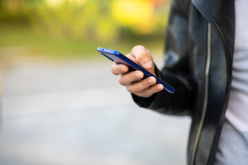 Closeup shot of an unrecognizable young man holding mobile phone in hand, blurred background