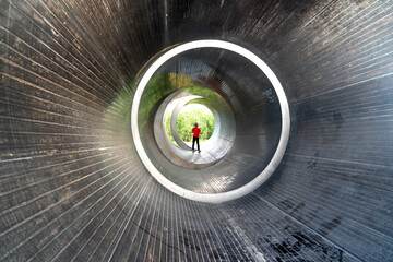Asian woman in red shirt practicing yoga on the background of concrete pipes Ho Chi Minh City, Vietnam