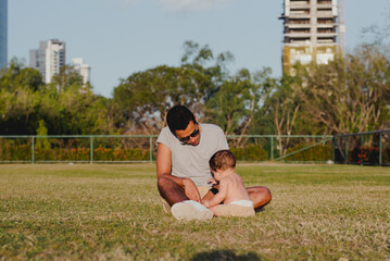 "Family Moment: Uncle and Infant Nephew Sitting on Grass Outdoors"

