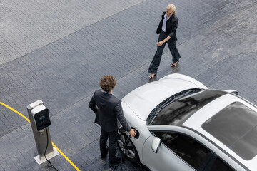 Aerial view progressive lifestyle of businesspeople with electric car connected to charging station...