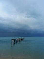 Ocean landscape with dark stormy sky and ruined jetty at Bophut beach on Koh Samui island in Thailand.
