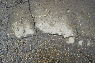 Old road background surface of gray cracked asphalt texture closeup. Old cracked asphalt. Grunge background. Wet