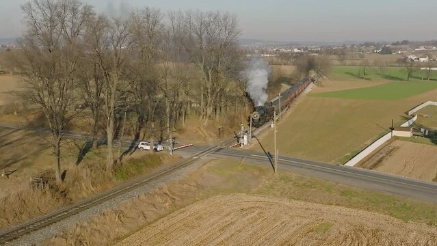 Drone Zoom out View, in Slow Motion, of an Approaching Steam Passenger Train, Approaching a Crossing