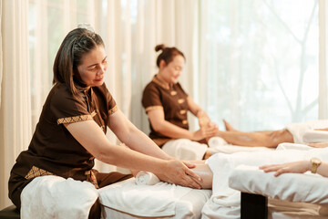 Obraz na płótnie Canvas Masseuse mature asian woman working massage service in spa salon, Foot and leg massage customer. Relaxing massage in spa salon concept.