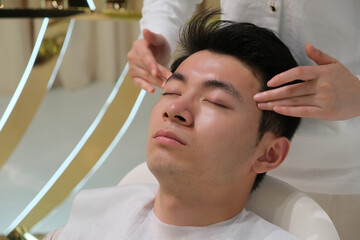 handsome Asian young man in head and face massage. facial massage, skincare and beauty treatment concept