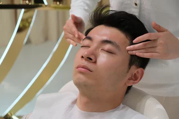 Peel and stick wall murals Spa handsome Asian young man in head and face massage. facial massage, skincare and beauty treatment concept