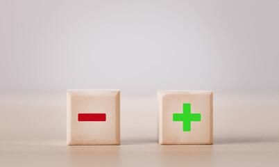 Wooden blocks showing plus and minus signs. The concept of antithesis. Decision making. Positive or...