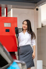 Woman unplugging the electric car charger at a downtown charging point